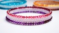 Beaded bracelet on white background with other bracelets. Pink, purple and red beads in repeating pattern. Blue, orange Royalty Free Stock Photo