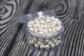 Beads for needlework. Pearl color. In a plastic jar. On pine boards painted black and white Royalty Free Stock Photo