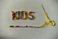 Beads strung on yellow cotton with a needle as a line under the inscription KIDS