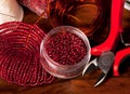 beadwork. Making handmade jewelry. Box with red beads on an old wooden background. Handmade accessories. View from above