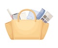 Beage handbag full of typical woman things and accessories as eyeshadow, lipstick, beige, haircomb, lotion, smartphone