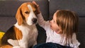 Beagle dog on couch with 2 year old girl bright room