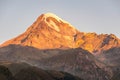 Beaitiful scenic view of KAzbek mountain top during sunrise and Gergeti church in foreground Royalty Free Stock Photo