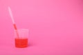 Beaker with liquid and stirring rod on bright pink background, space for text. Kids chemical experiment toy