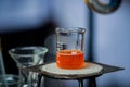 orange colored chemical solution in a chemical measuring cup