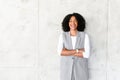 A beaming African-American woman stands confidently, her arms crossed