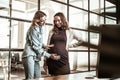 Beaming blonde friend rubbing pregnant belly of her dark-haired colleague