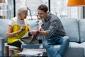 Beaming charming woman recommending furniture upholstery sample to son