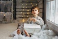 Beaming curlyhair boy opening his christmas gift. New Year lights background