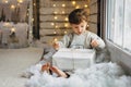 Beaming curlyhair boy opening his christmas gift. New Year lights background