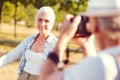 Beaming elderly woman looking at husband photographing her Royalty Free Stock Photo