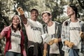 Beaming funny students wearing white shirt with volunteer sign cleaning forest Royalty Free Stock Photo