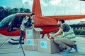 Beaming good-looking guys taking out clothes from boxes with aid