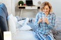 Beaming good-looking mature lady sitting on the bed in bright pajama
