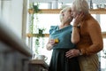 Beaming husband and wife embracing and kissing at the kitchen.