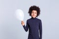 Beaming little boy standing on monochromic background and carrying