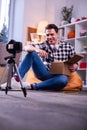 Beaming positive man sitting on the floor during shooting process