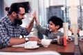 Beaming son giving high five father after studying foreign language