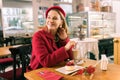 Beaming mature woman drinking latte and eating dessert in cozy bakery