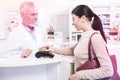 Beaming woman using a credit card paying for her medication