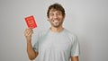 Beaming young man joyfully presents his pass, a singapore passport, confidently standing isolated on a white background Royalty Free Stock Photo