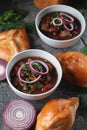 Bean soup with herbs and red onion rings in two small white bowls with fresh rye bread and garlic Royalty Free Stock Photo