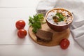 Bean soup with vegetables, olives, cheese and fresh herbs in a ceramic bowl, next to rye bread, tomatoes on a wooden stand. White Royalty Free Stock Photo