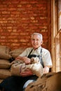 These beans are ready for brewing. Cropped portrait of a senior man holding a sack of coffee beans while sitting in a