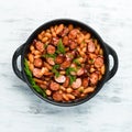 Beans with sausages in tomato sauce on a black plate. Top view. Royalty Free Stock Photo