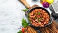 Beans with sausages in tomato sauce on a black plate. Top view. Royalty Free Stock Photo