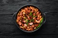 Beans with sausages in tomato sauce on a black plate.  Top view. Royalty Free Stock Photo