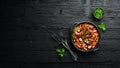 Beans with sausages in tomato sauce on a black plate. Top view. Royalty Free Stock Photo
