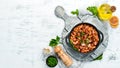 Beans with sausages in tomato sauce on a black plate. Top view. Royalty Free Stock Photo