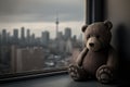 bear doll sitting on windowsill, with the view of the city skyline