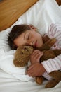 Bear is my bedtime pal. a cute little girl holding her teddybear while sleeping in bed.