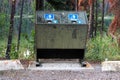 A bear proof garbage container along side a parking lot