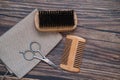 Beard kit with scissors, comb and brush on wooden background. Top view