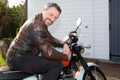 Beard man in brown leather motorbike fashion jacket sit on vintage retro motorcycle outdoors Royalty Free Stock Photo