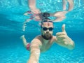 Beard man with glasses diving in a blue clean water with thumb u Royalty Free Stock Photo