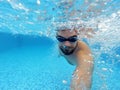 Beard man with glasses swimming under water in the pool Royalty Free Stock Photo