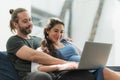 Beard man and his pregnant wife watching movie on laptop feeling happy while sitting on sofa in the home. Family concept Royalty Free Stock Photo