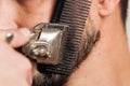 Beard trimming with an old beard shaving machine. Bearded man shaving his beard Royalty Free Stock Photo