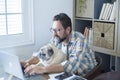 Bearded adult man work at home in office room with his friend dog - people and modern job lifestyle with internet connection and Royalty Free Stock Photo