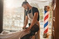 Cheerful barber trimming client beard in barbershop Royalty Free Stock Photo