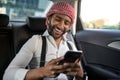 Bearded Indian Muslim businessman using smart phone in taxi cab