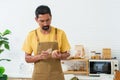 Bearded Asian man in overalls standing in kitchen was using his hand to peel the skin of potato that was ready to eat. to prepare Royalty Free Stock Photo