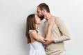 Bearded attractive guy kissing his woman on her forehead