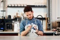 Bearded barista drys jug with towel