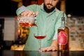 Bearded barman pouring an alcoholic drink into a glass Royalty Free Stock Photo