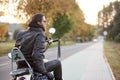 Bearded biker in black leather jacket on modern motorcycle on country roadside. Royalty Free Stock Photo